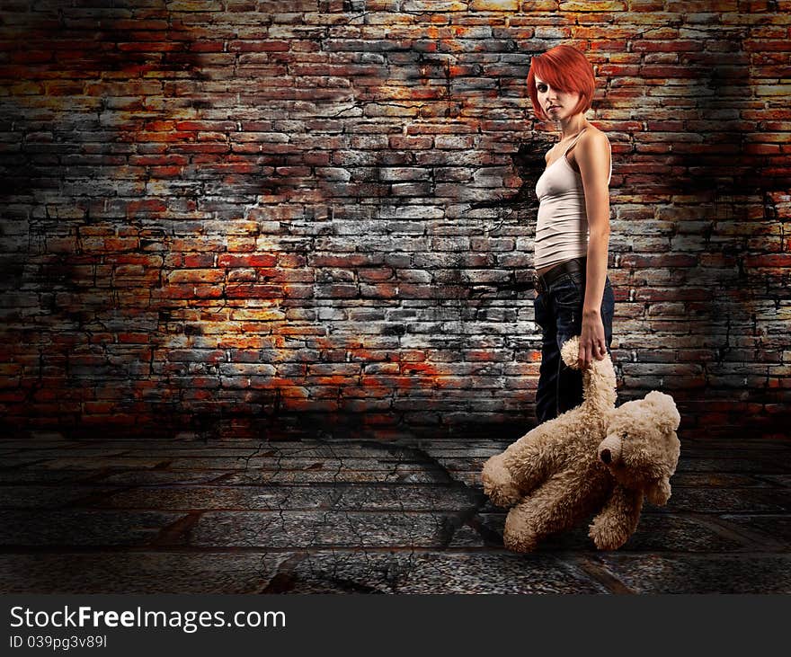 The girl with a teddy bear against a brick wall