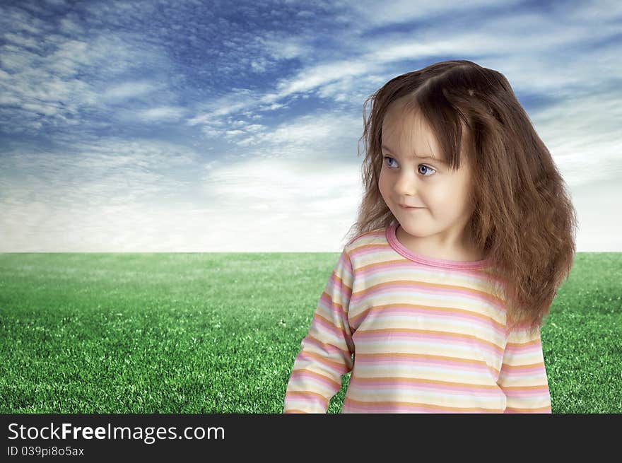 The smiling child against the blue sky and a green field