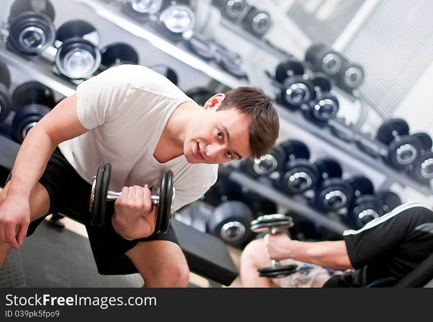 Young man lifting bumbbell in sport club