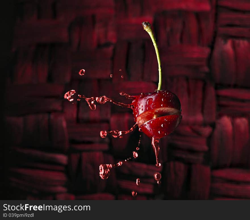 Red chery with liquid splash of juice on red background