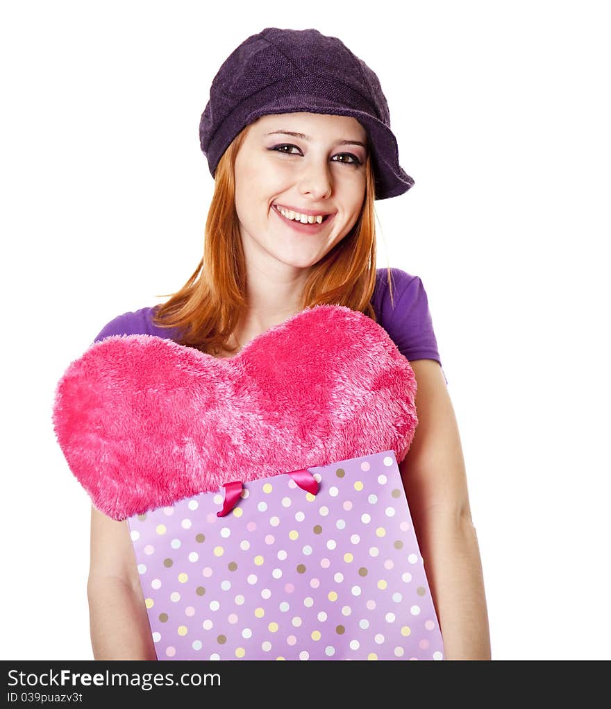 Beautiful red-haired girl with heart in bag. Studio shot.