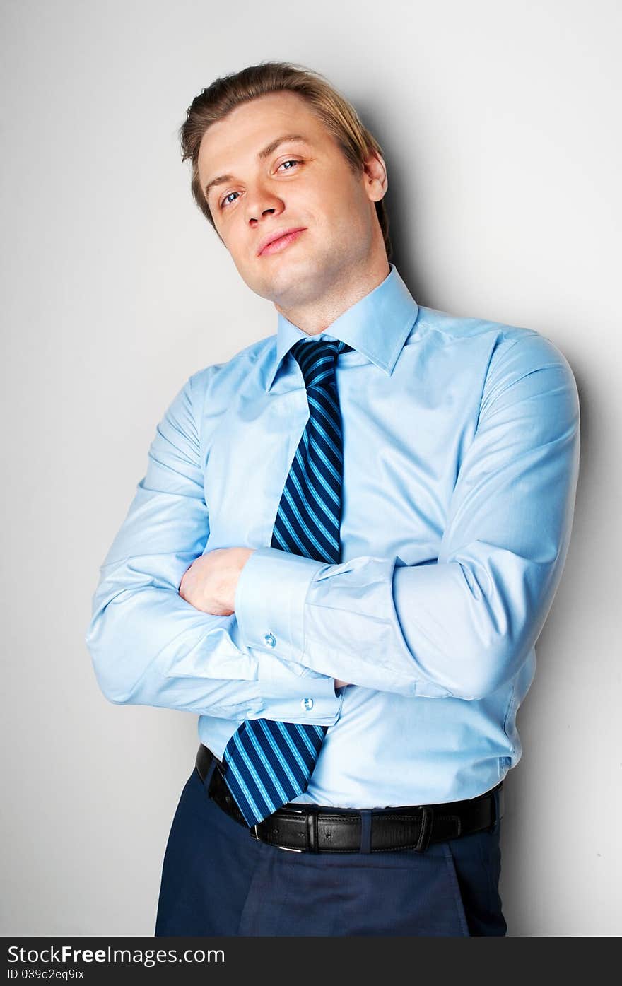 Handsome young smiling man standing near the wall