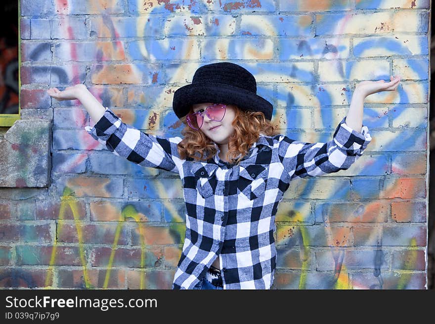 Red haired little girl in front of brick wall