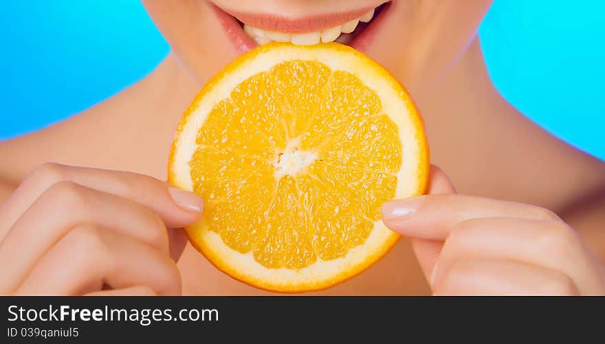 Woman with relish eating a slice of orange