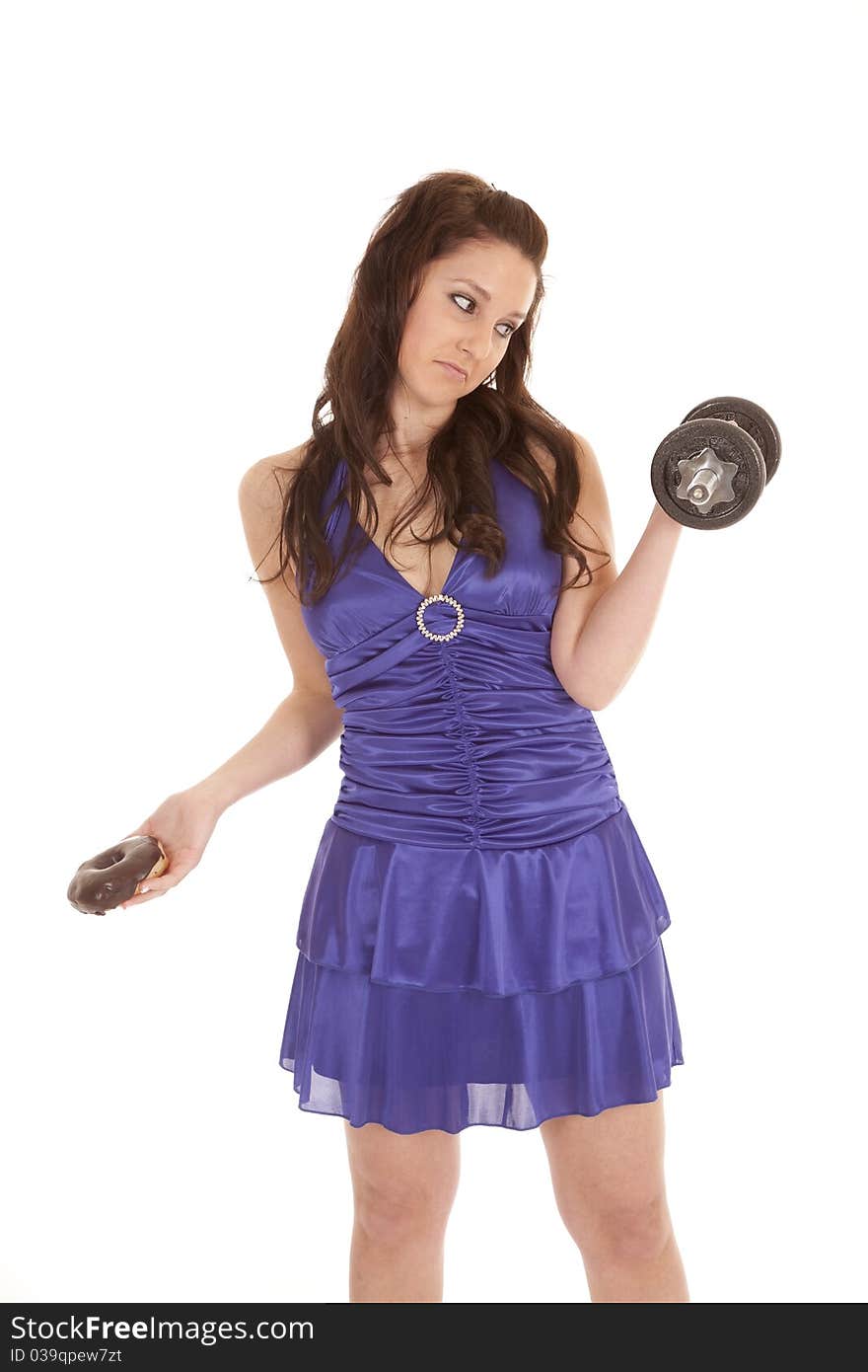 A woman in a blue dress is holding a weight and a donut. A woman in a blue dress is holding a weight and a donut.