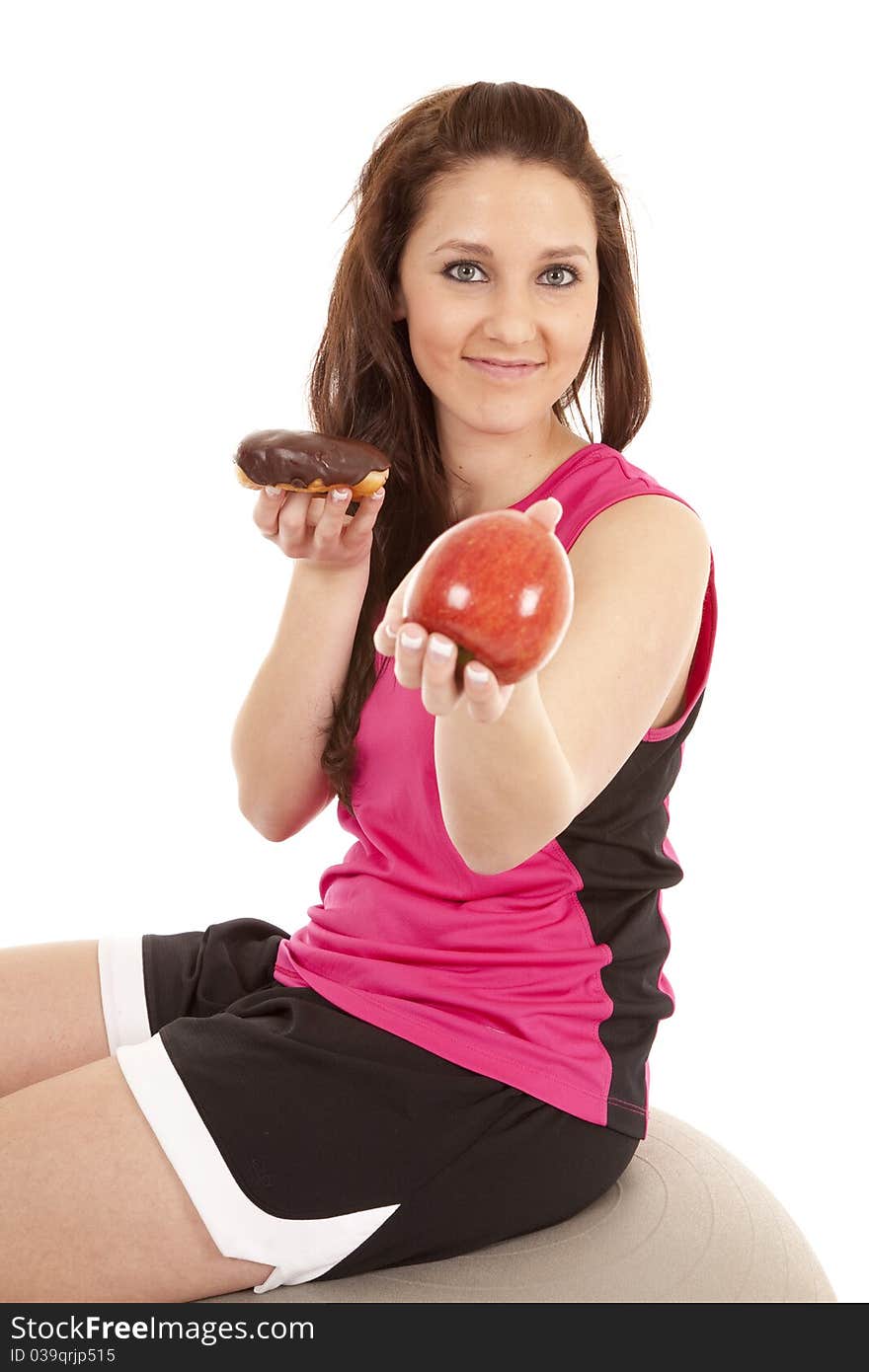 A woman in fitness attire is handing an apple and keeping the donut. A woman in fitness attire is handing an apple and keeping the donut.