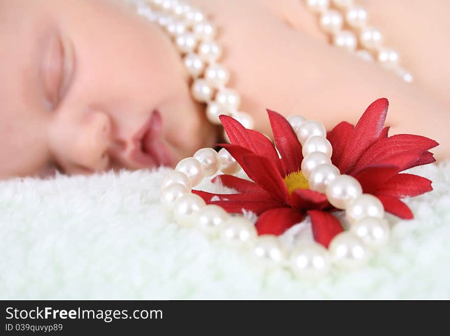 Beautiful baby girl sleeping, pearls draped with flower. FOCUS ON FLOWER AND PEARLS. Beautiful baby girl sleeping, pearls draped with flower. FOCUS ON FLOWER AND PEARLS.