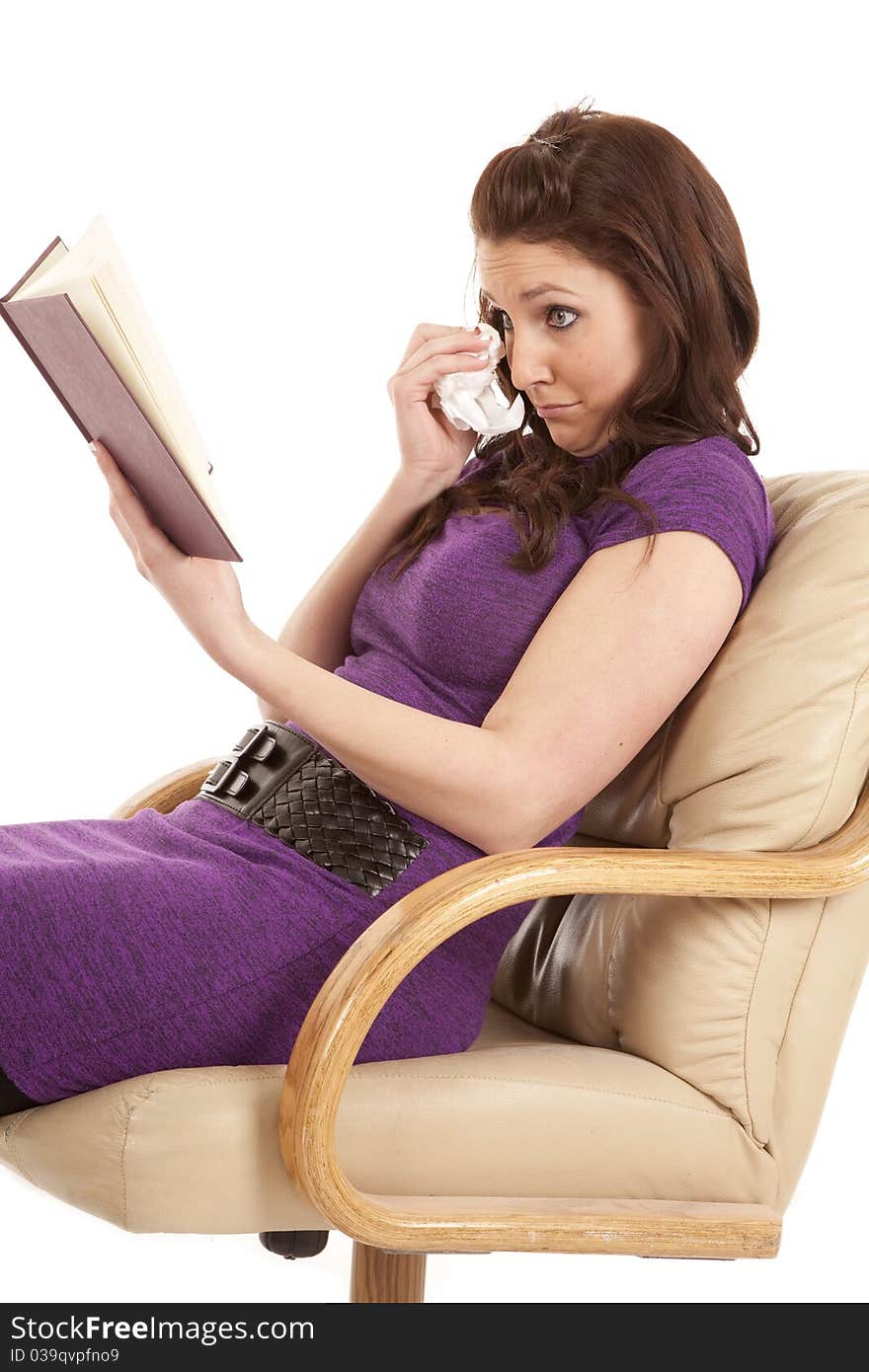 A woman is reading a book and holding a tissue to her face. A woman is reading a book and holding a tissue to her face.