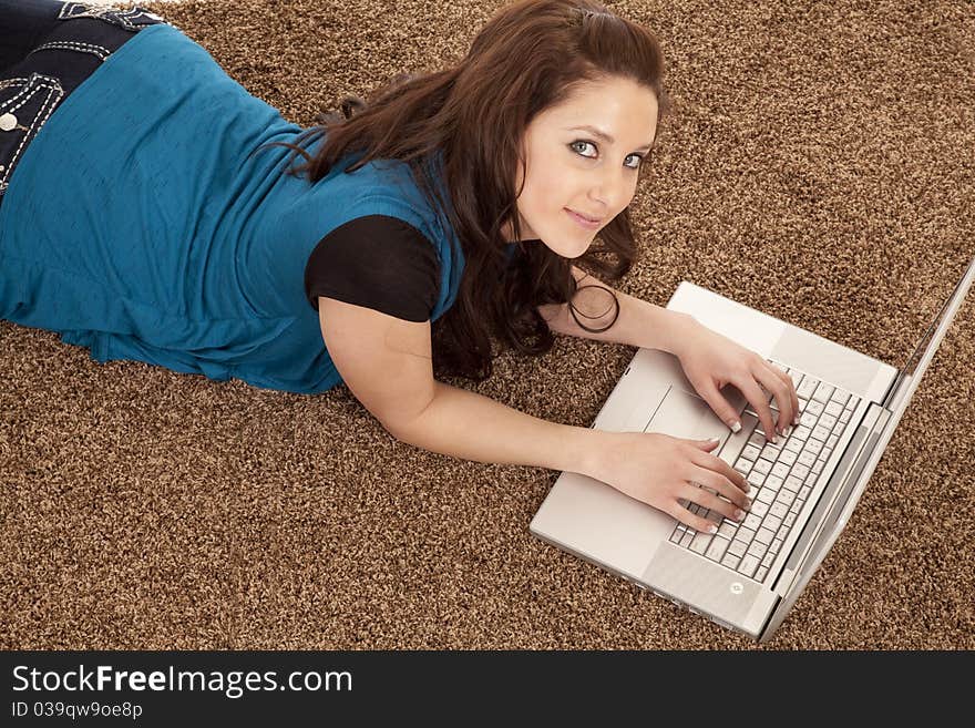 A woman is laying on the floor with a computer looking up. A woman is laying on the floor with a computer looking up.