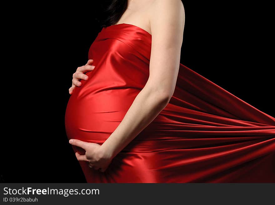 Pregnant young woman in red satin. Pregnant young woman in red satin