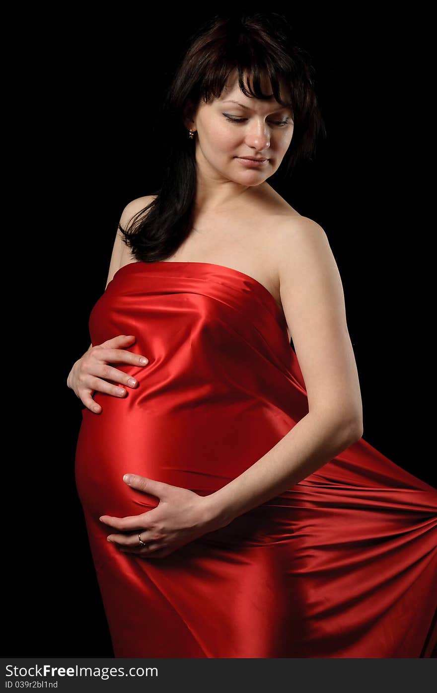 Pregnant young woman in red satin. Pregnant young woman in red satin