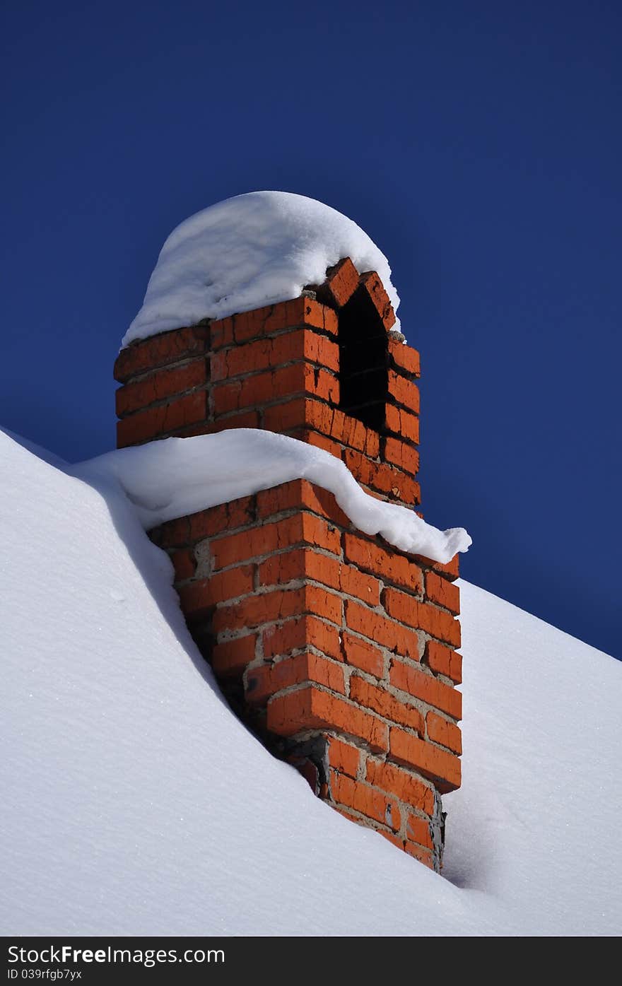 Russian winter: chimney and cottage roof all covered with snow against deep blue frozen sky. Russian winter: chimney and cottage roof all covered with snow against deep blue frozen sky