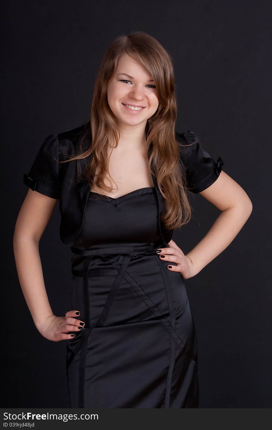 A young girl in a black dress holding hands at the waist. A young girl in a black dress holding hands at the waist