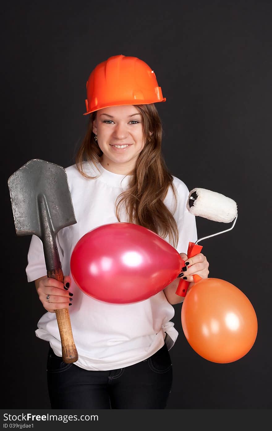 The girl in the orange helmet with balls and a shovel