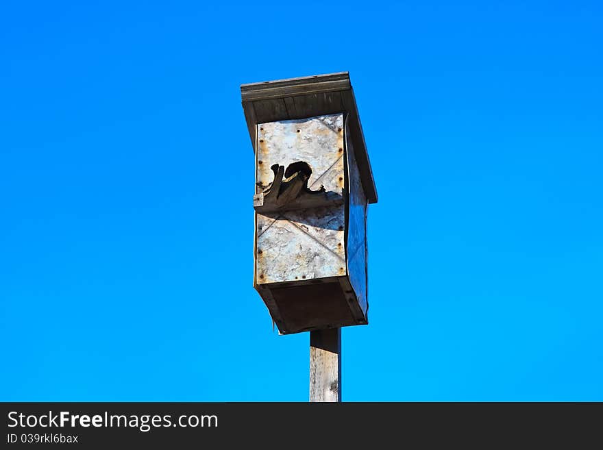 Very old bird house bright blue sky. Very old bird house bright blue sky