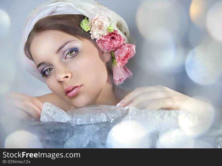 A beautiful young girl on her head scarf and flowers. Before her ice cubes and flashing light. A beautiful young girl on her head scarf and flowers. Before her ice cubes and flashing light