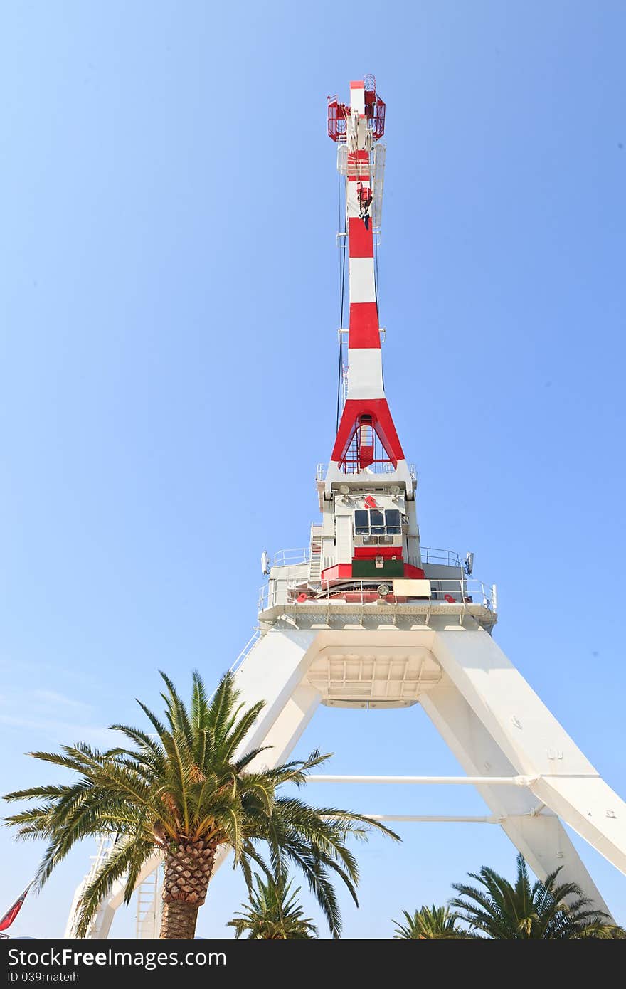 Industrial crane and palm tree against a blue sky. Industrial crane and palm tree against a blue sky