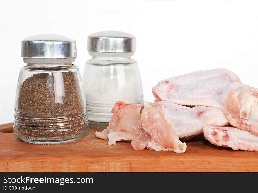 Raw chicken on plate with salt and pepper