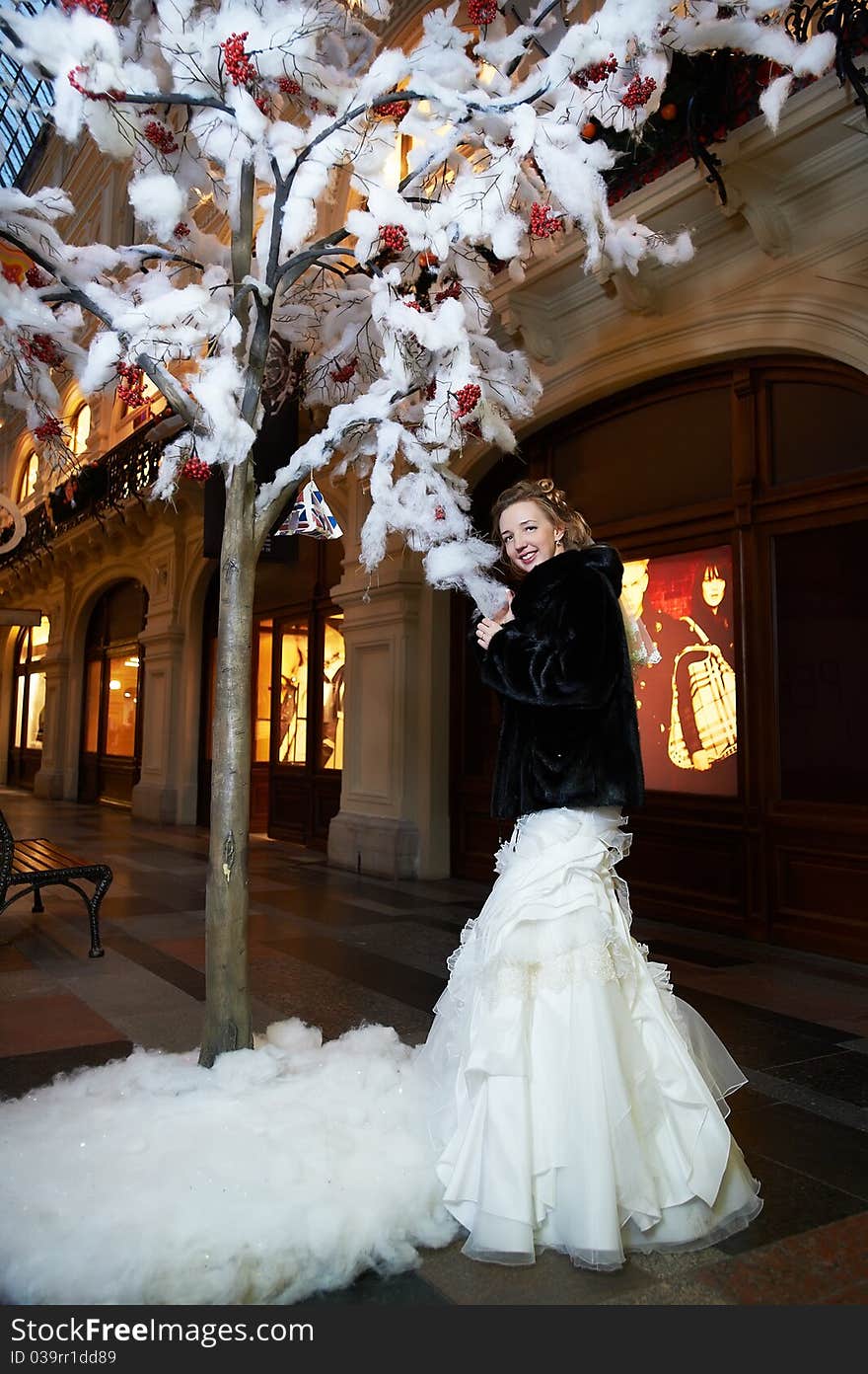 Beauty bride near artifical tree in big shop at wedding day