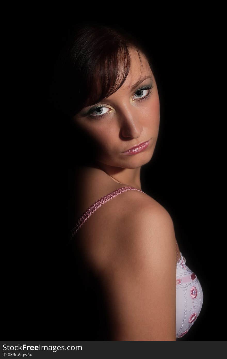 Portrait of young girl in lingerie standing before black background