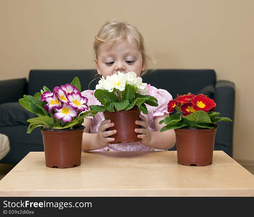 Girl sitting at a table and holding flowers in her hands. Girl sitting at a table and holding flowers in her hands