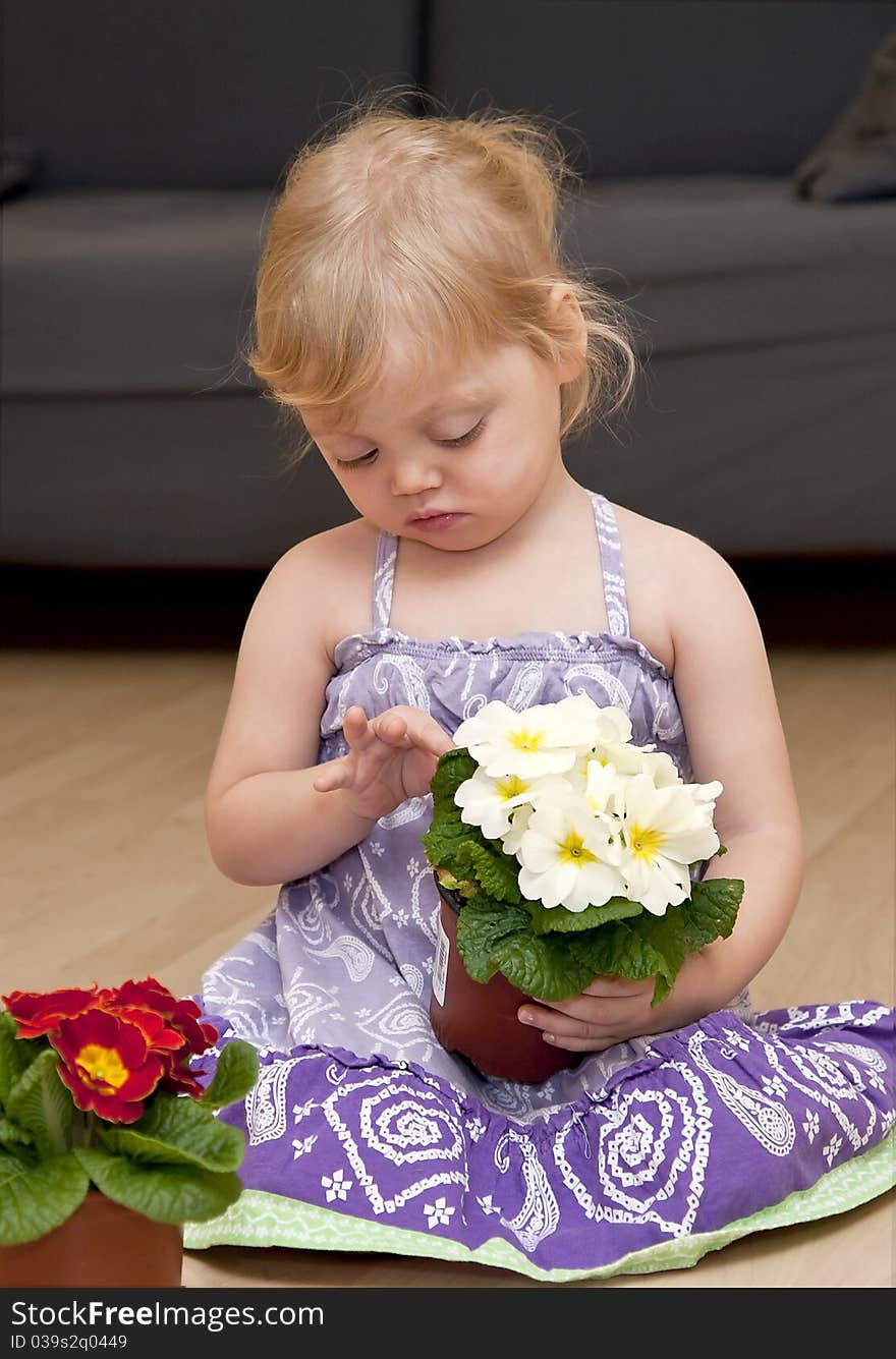 Girl sits on the floor and holds flowers in pots in her hands. Girl sits on the floor and holds flowers in pots in her hands