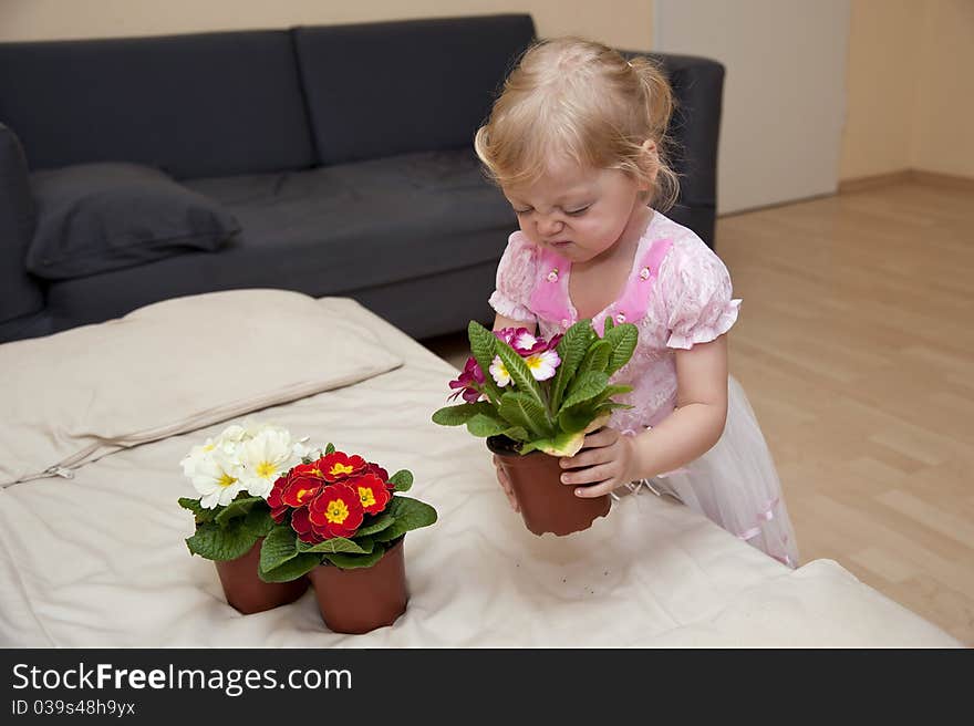 Girl smelled the pink flower and puts it now on the sofa next to the other two. Girl smelled the pink flower and puts it now on the sofa next to the other two