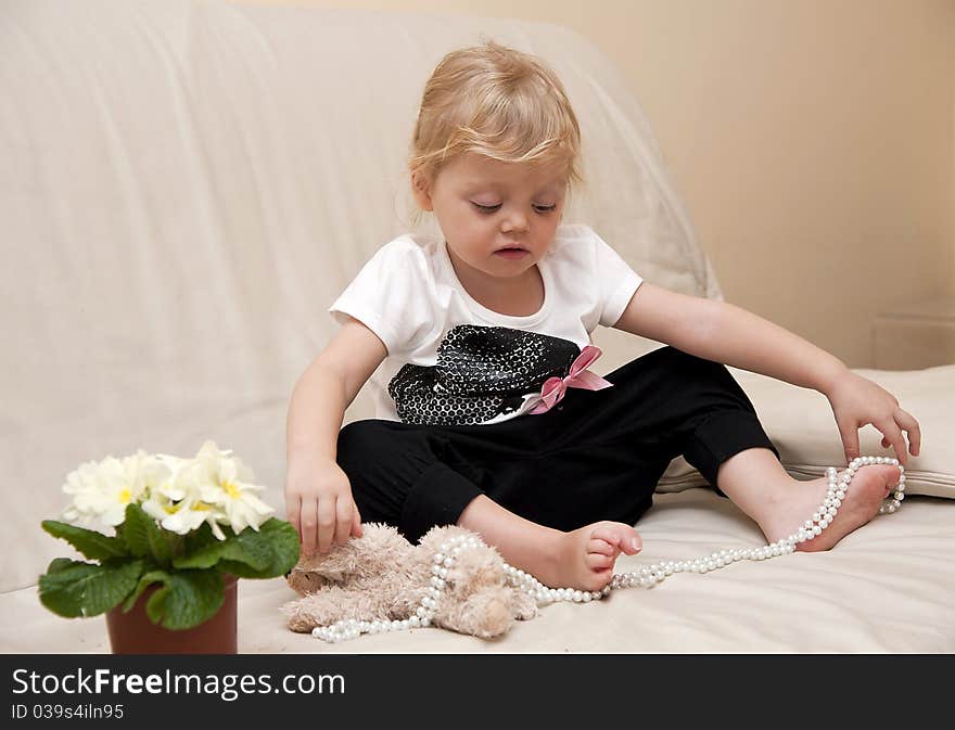 Girl sitting on a sofa and playing with beads