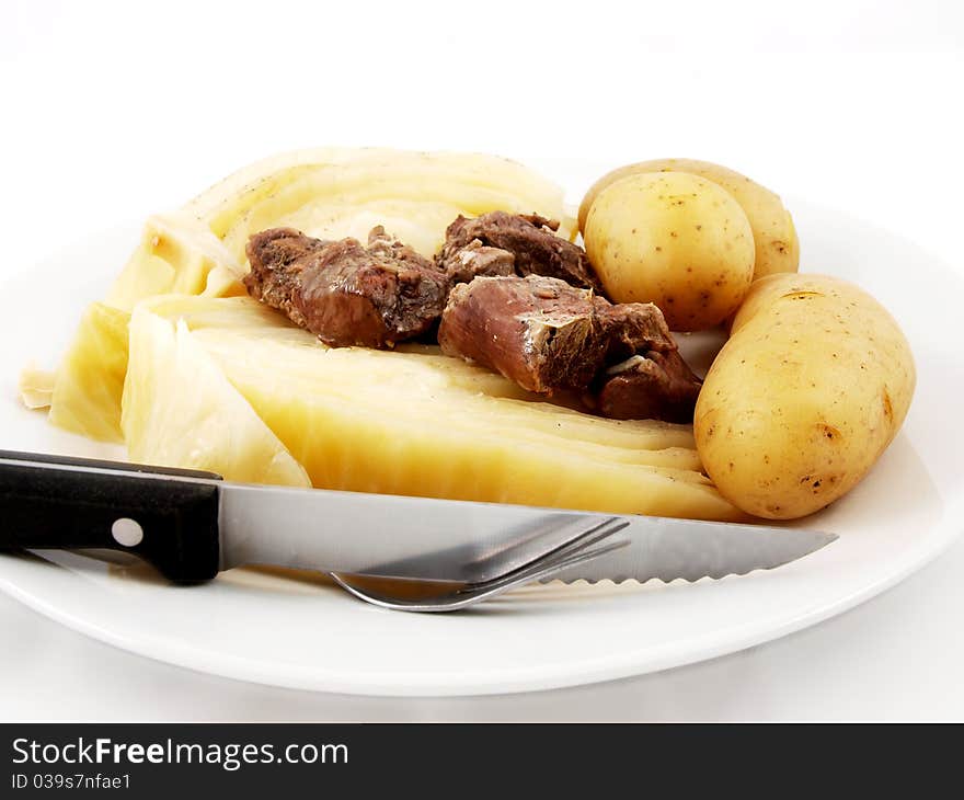 Mutton with cabbage, knife and  fork on white plate towards white background