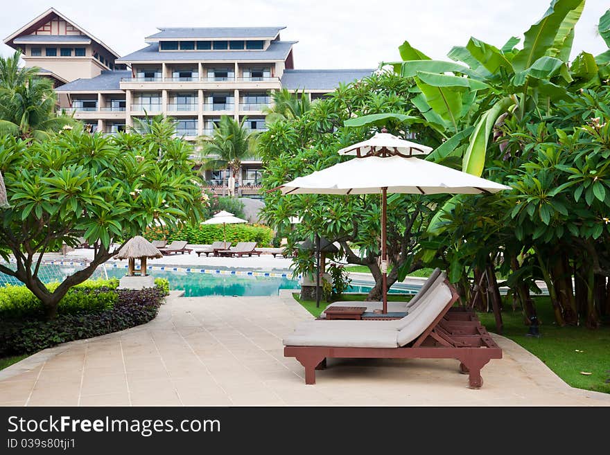 Hotel garden with swiiming pool and relaxing chairs at poolside.