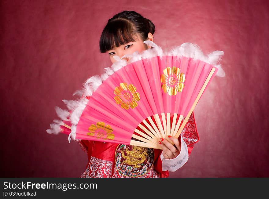 Asian model in traditional dress with the fan on the red background. Asian model in traditional dress with the fan on the red background.