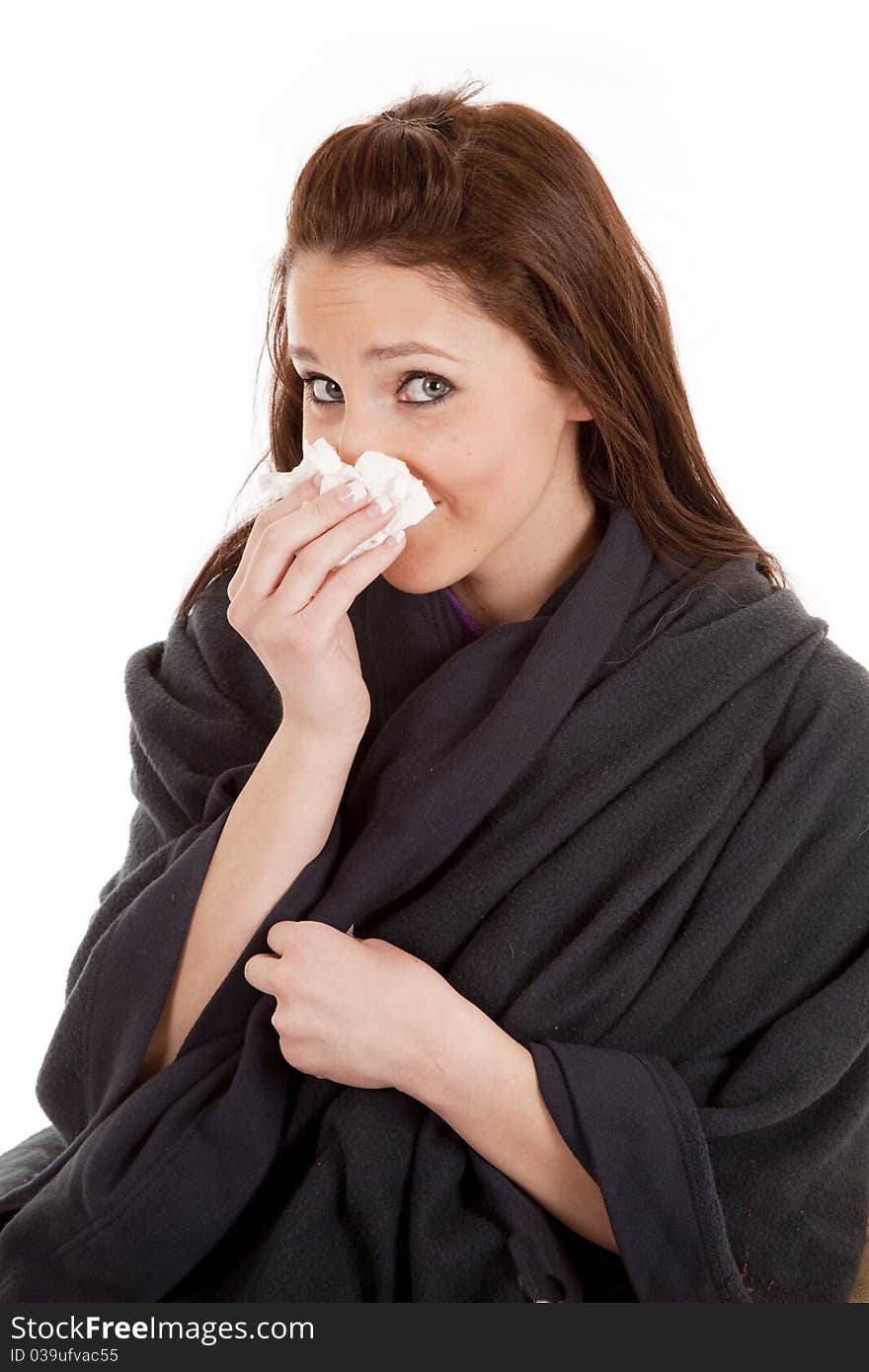 A woman is wrapped in a warm blanket and has a tissue. A woman is wrapped in a warm blanket and has a tissue.