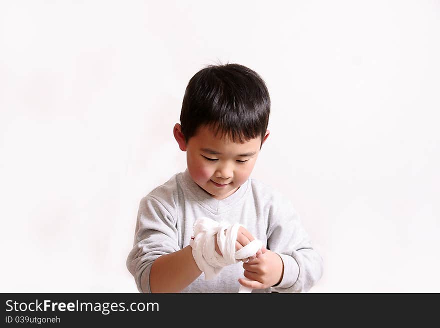 Picture of a little chinese boy winding bandage on hand by himself