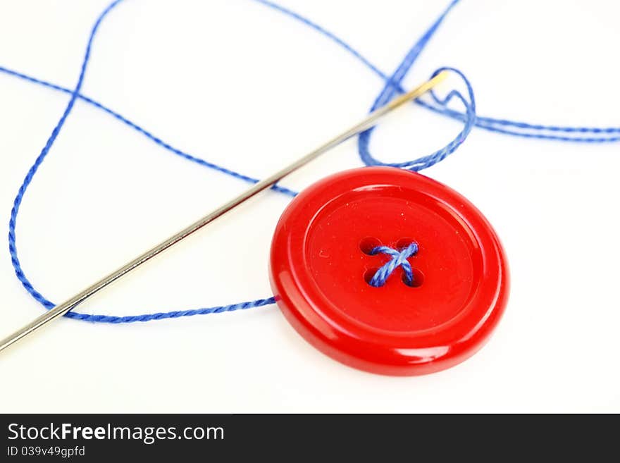 Button with needle and thread isolated on white background