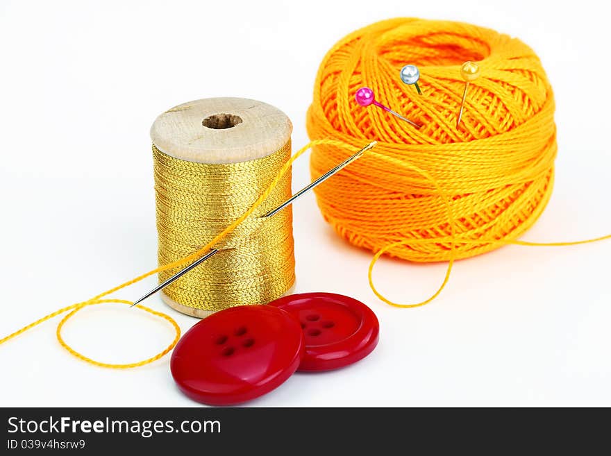 Colored thread, needles and buttons on a white background