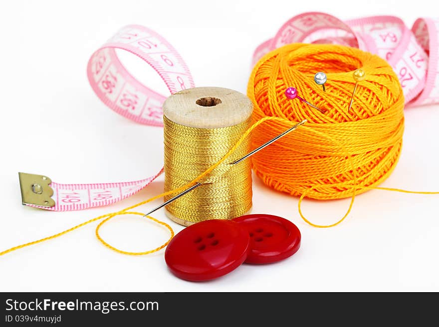 Colored thread, needles and buttons on a white background