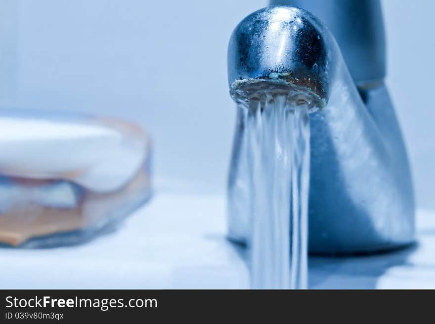 Cool toned and desaturated flowing faucet with shallow focus. Cool toned and desaturated flowing faucet with shallow focus.