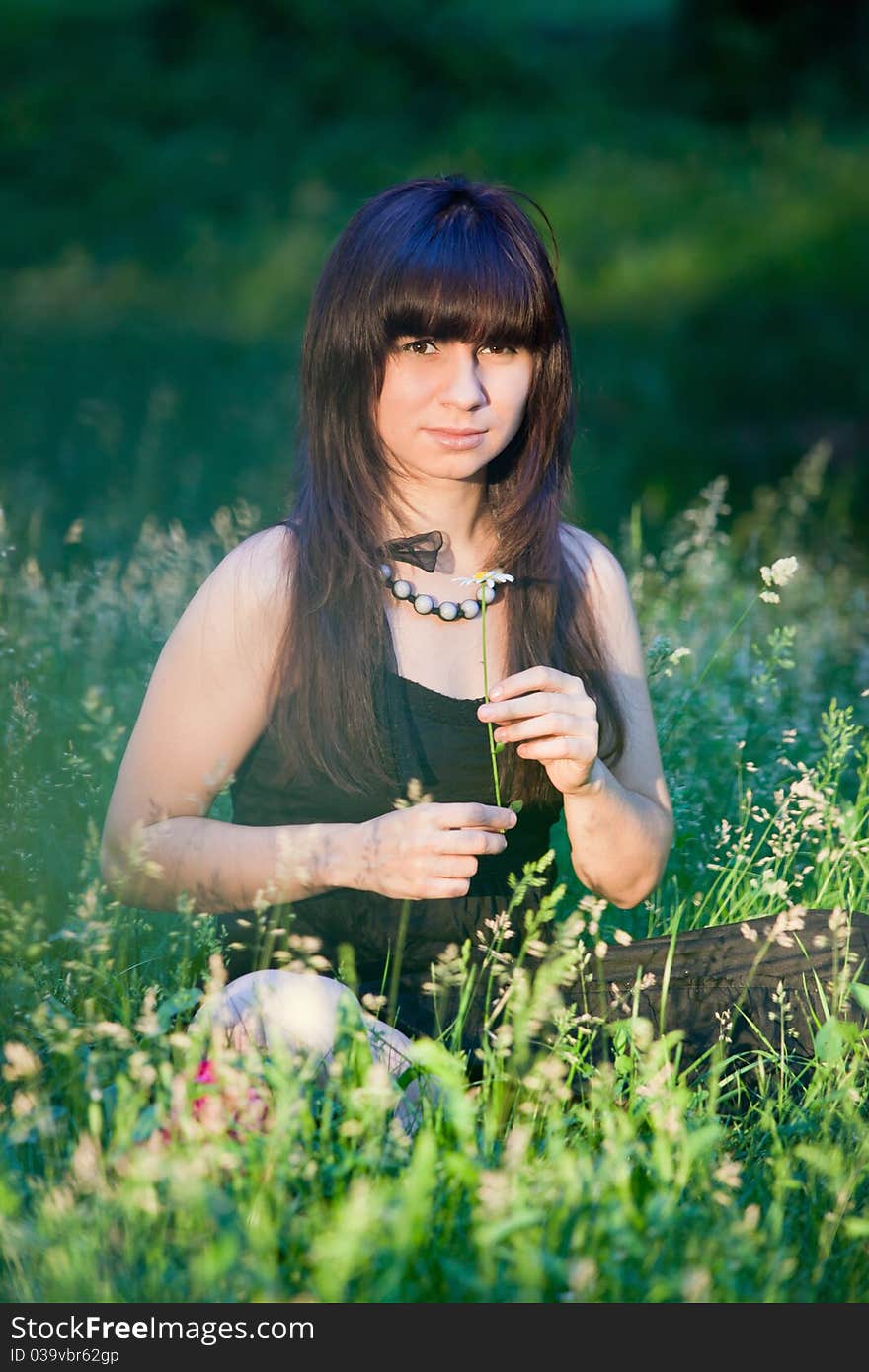 beautiful girl sits in a green grass. beautiful girl sits in a green grass