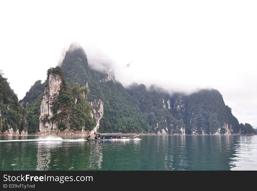 Long tailed boat cruise on emerald lake with limestone mountain background. Long tailed boat cruise on emerald lake with limestone mountain background.