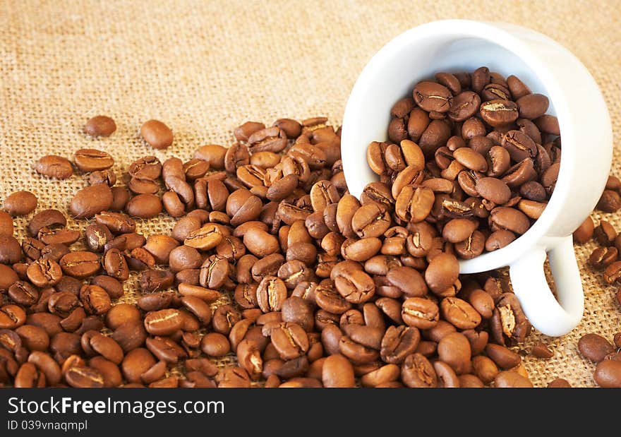 Small espresso cup filled with roasted coffee beans. Small espresso cup filled with roasted coffee beans