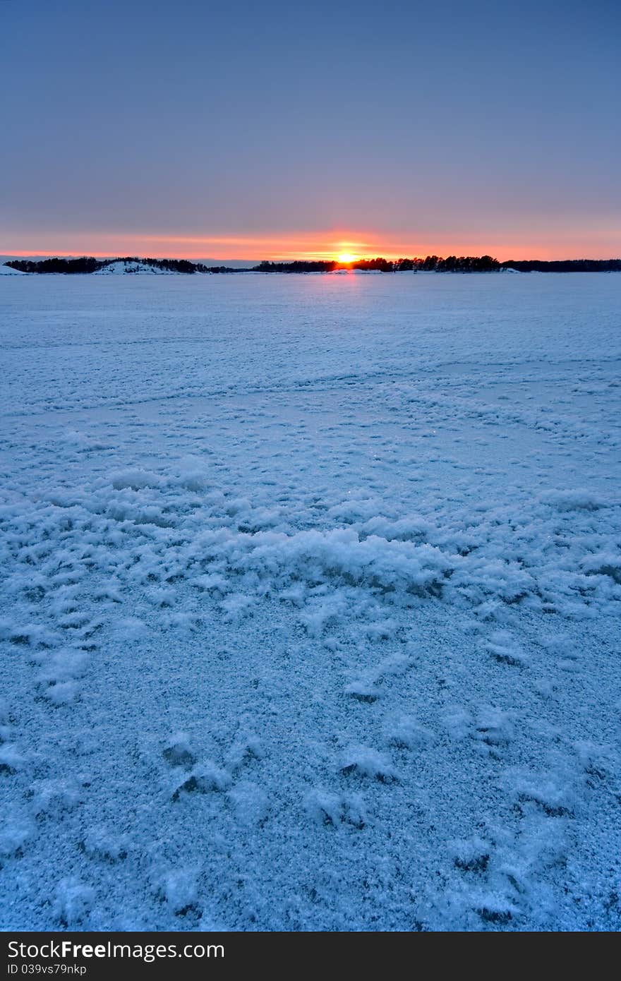 This is a vertical photo taken after sunset in the coast of  Helsinki. There is  icy sea in the foreground. This is a vertical photo taken after sunset in the coast of  Helsinki. There is  icy sea in the foreground.