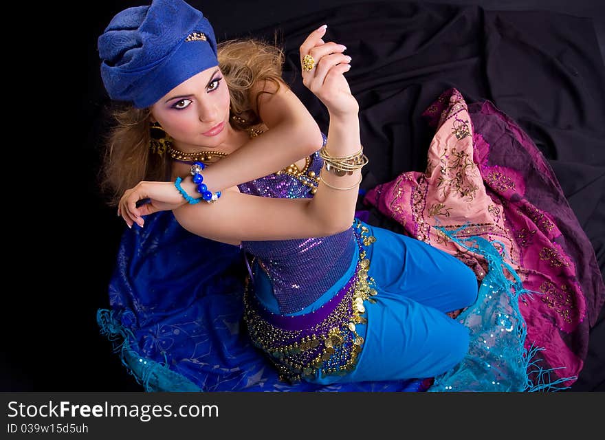 Beautiful girl in a turban and a stylized ethnic costume sits on headscarves