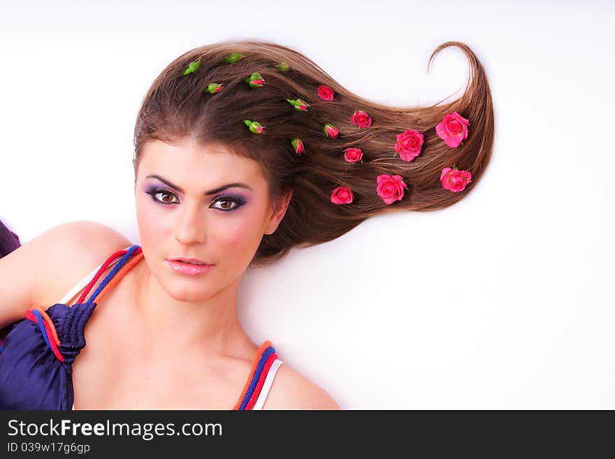 Pretty girl lying with flowers-roses in her hair