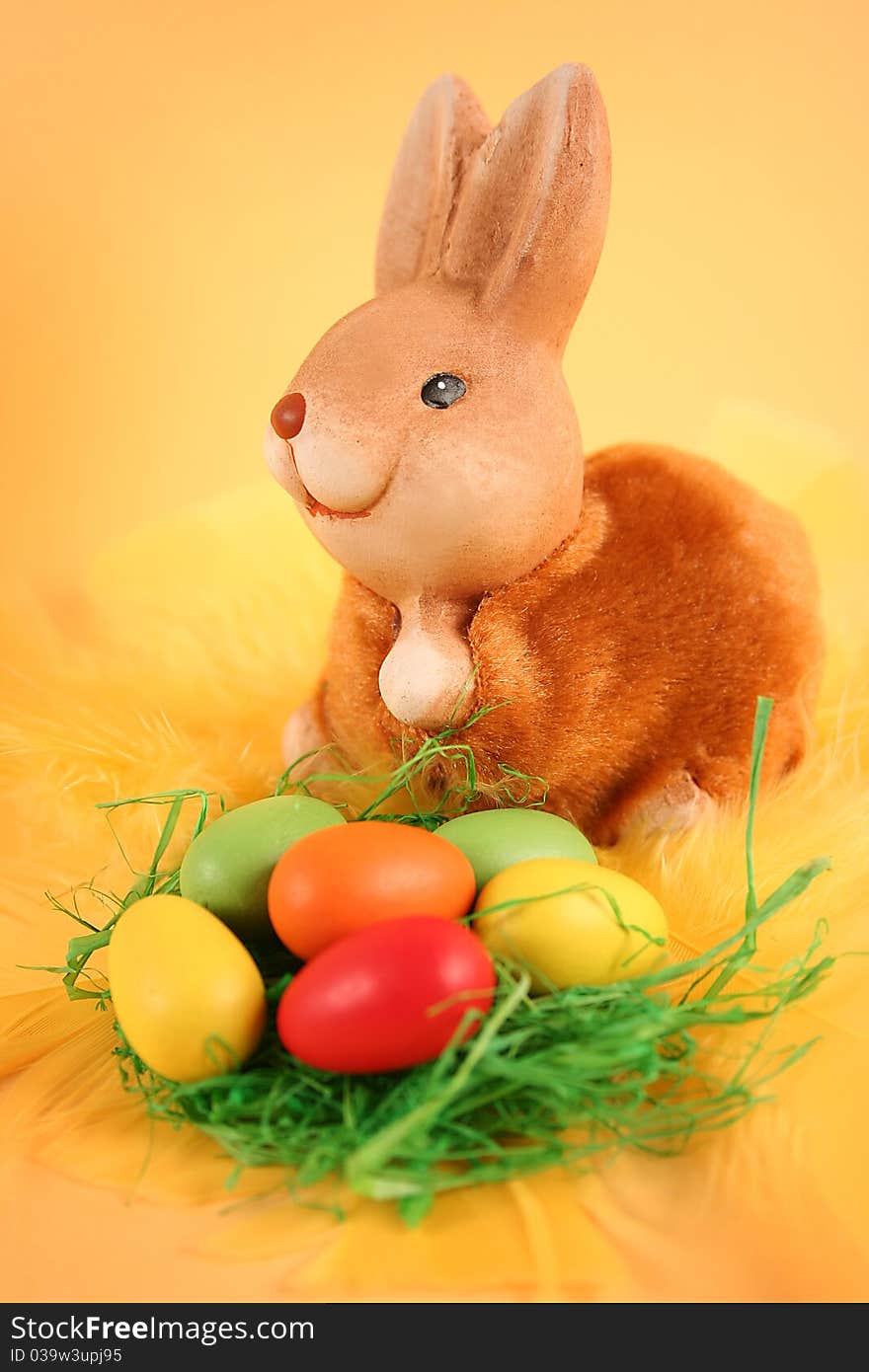 Easter bunny with colored eggs on yellow background