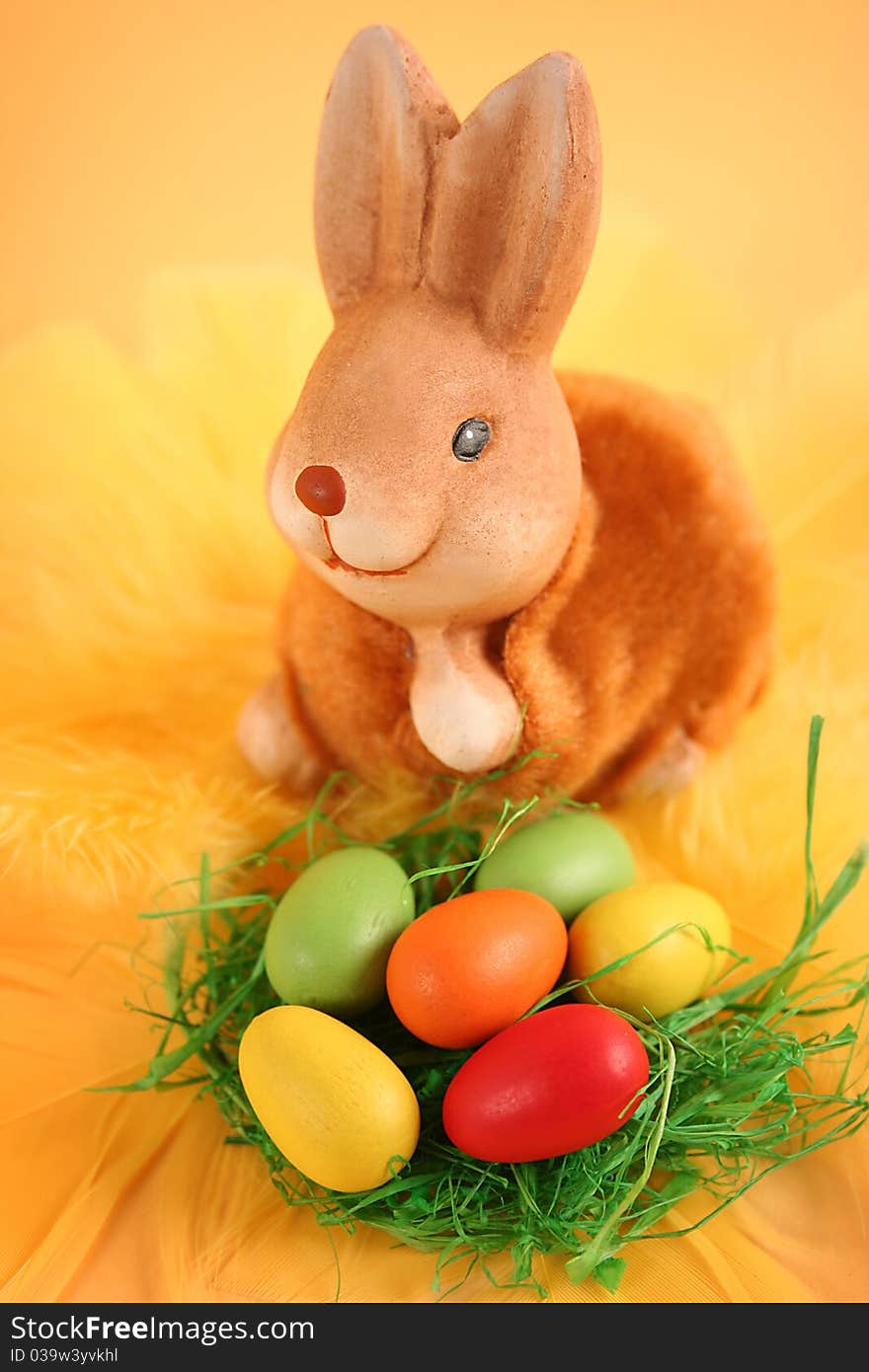 Easter bunny with colored eggs on yellow background