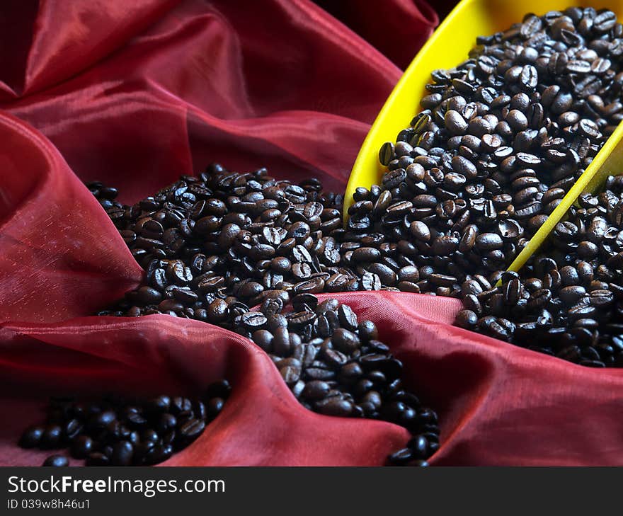 The image shows a part of a blade filled with coffee beans over a red shawl