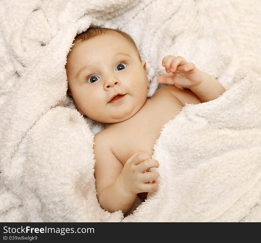 The baby lies in a white towel. He smiles. The baby lies in a white towel. He smiles