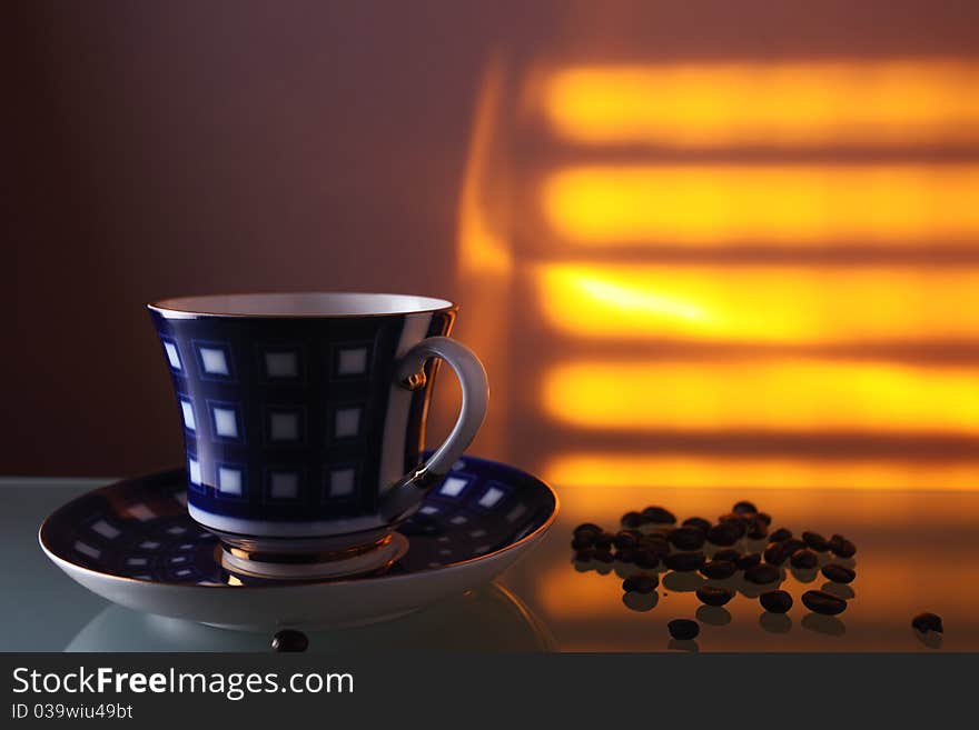 Cup and coffee beans on a glass table.