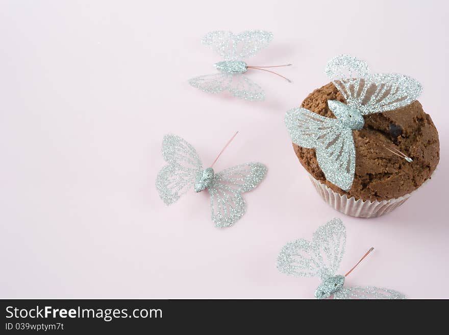 Chocolate muffin on a pink background with butterflies. Chocolate muffin on a pink background with butterflies