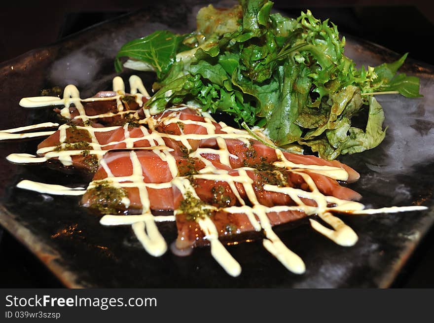 A closeup of a Japanese style raw salmon salad, dressed with sesame dressing and mayonnaise.